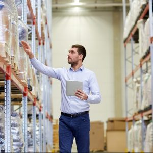 wholesale, logistic, business, export and people concept - man or manager with tablet pc computer checking goods at warehouse